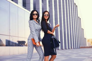 Şehir merkezinde bir gökdelenin bir arka plan ayakta şık bir resmi elbise iki iş kadın portresi giymiş.