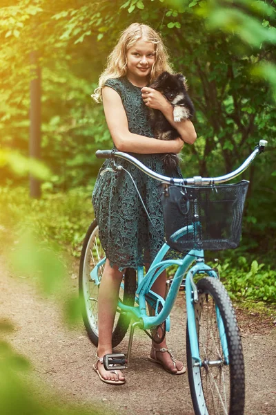 一个小金发女孩的肖像在休闲礼服, 持有可爱的斯皮茨狗, 在公园. — 图库照片