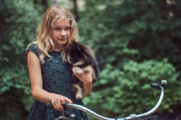 Portret dziewczynki Blondynka w strój, posiada ładny spitz pies, w parku. — Zdjęcie stockowe