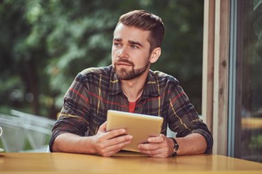 Bir kafe içinde bir tablet bilgisayarda çalışma Polar gömlek giymiş yakışıklı şık erkek freelance şık saç ve sakal,.