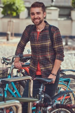 Polar gömlek giymiş bir yakışıklı şık genç erkek ile şık saç ve sakal, Bisiklet Park park yerinde duruyor.