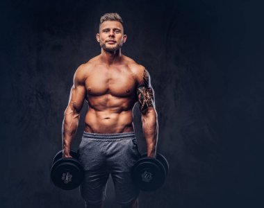 Bir stüdyoda poz spor şort giyen bir yakışıklı gömleksiz dövmeli vücut geliştirmeci şık saç ve sakal, ile. Karanlık bir arka plan üzerinde izole