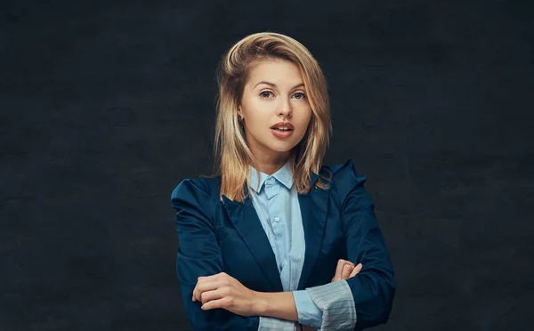 Portrait of a sensual blonde business woman dressed in a formal suit and blue shirt, posing in a studio. Isolated on a dark background. — Stock Photo, Image