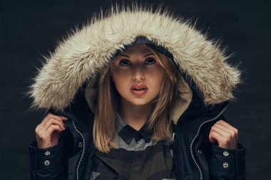 Bir stüdyoda ayakta bir kış ceket ve Polar gömlek, bir seksi sarışın kız portresi.