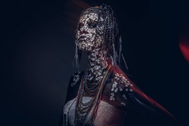 Yakın çekim bir cadıdan geleneksel kostüm giyen Yerli Afrikalı kabile portresi. Kalıcı makyaj kavramı. Karanlık bir arka plan üzerinde izole.