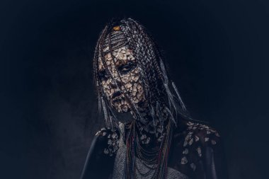 Korkunç bir Afrika şaman taşlaşmış ile kadın portresi cilt ve dreadlocks karanlık bir arka plan üzerinde kırık. Kalıcı makyaj kavramı.