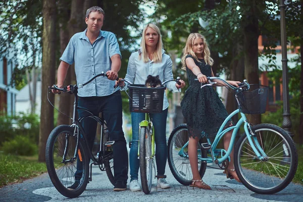 一个有吸引力的家庭穿着休闲衣服骑自行车与他们可爱的小斯皮茨狗 — 图库照片