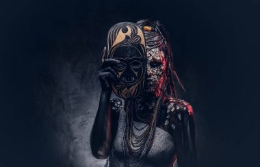 Taşlaşmış bir kırık Cilt ve dreadlocks, korkutucu Afrika şaman erkek portresi geleneksel maske karanlık bir arka plan üzerinde tutar. Kalıcı makyaj kavramı.
