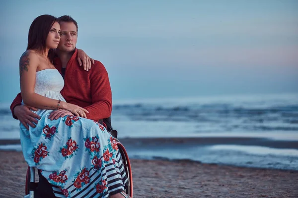 愛するカップル背景明るい夜明けのビーチで休んで彼女の夫の膝の上に女性が座っています — ストック写真
