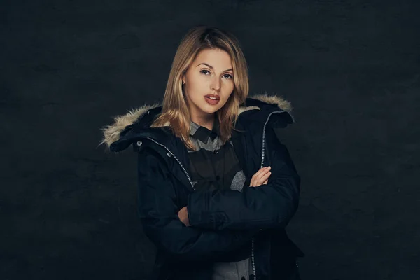 Retrato de una chica rubia sexy con chaqueta de invierno y camisa polar, de pie en un estudio . — Foto de Stock