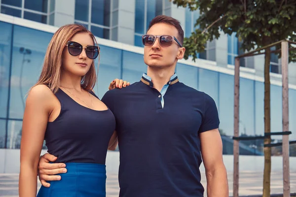 Atractiva pareja de moda, sexy chica rubia y hombre guapo de pie en la ciudad moderna contra un rascacielos . —  Fotos de Stock