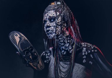 Yakın çekim bir cadıdan geleneksel kostüm giyen Yerli Afrikalı kabile portresi. Kalıcı makyaj kavramı. Karanlık bir arka plan üzerinde izole.