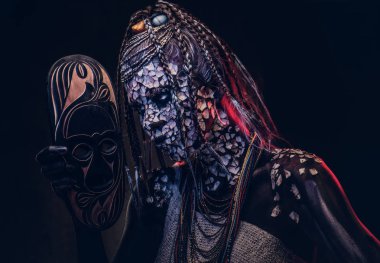 Yakın çekim bir cadıdan geleneksel kostüm giyen Yerli Afrikalı kabile portresi. Kalıcı makyaj kavramı. Karanlık bir arka plan üzerinde izole.