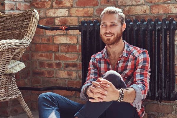 Jovem bonito ruiva modelo homem senta-se em um piso na sala com um interior loft . — Fotografia de Stock