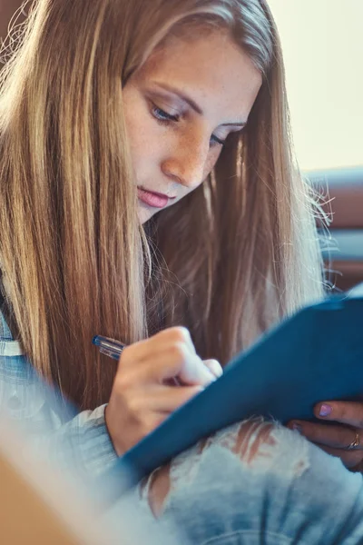 Portrait d'une charmante fille prenant des notes dans un bloc-notes, assise dans une voiture . — Photo