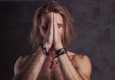 Portrait of shirtless redhead handsome man, prays.  Isolated on a dark background. clipart