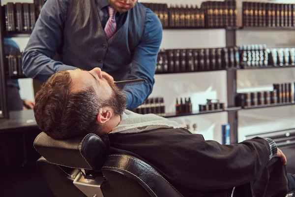 Professionell frisör modellering skägg med sax och kam på barbershop. — Stockfoto