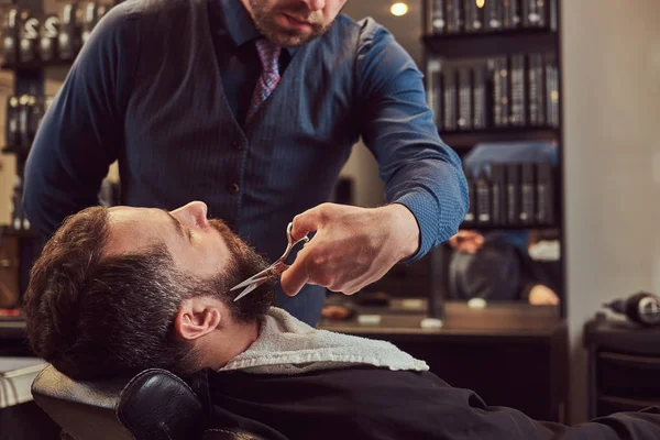 Profesionální kadeřník modelování vousy s nůžky a hřeben v holičství. — Stock fotografie