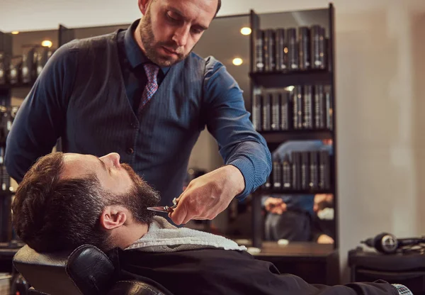 Peluquería profesional modelando barba con tijeras y peine en la barbería . —  Fotos de Stock