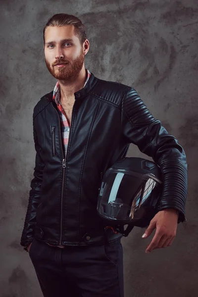 Портрет красивого стильного рыжего байкера в черной кожаной куртке, держит мотоциклетный шлем, позирует в студии . — стоковое фото