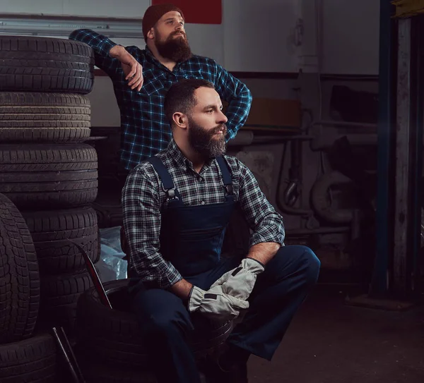 Dos Mecánicos Barbudos Cerca Una Pila Neumáticos Automóviles Viejos Garaje —  Fotos de Stock