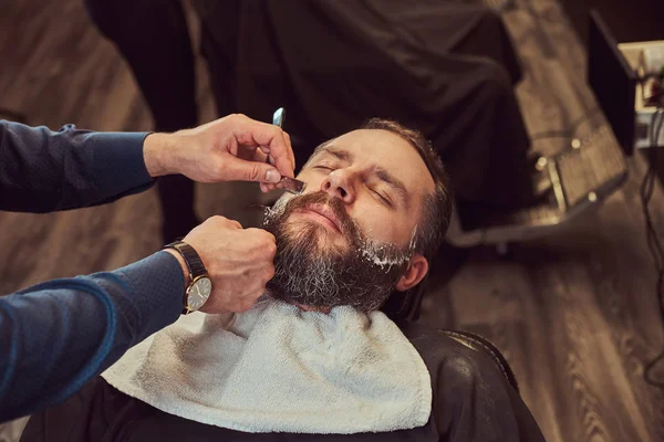 Guapo Hombre Barbudo Hipster Sentado Sillón Una Peluquería Mientras Peluquera —  Fotos de Stock