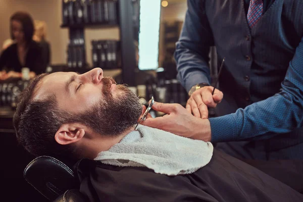 Homem Barbudo Sentado Uma Poltrona Uma Barbearia Enquanto Cabeleireiro Modelando — Fotografia de Stock
