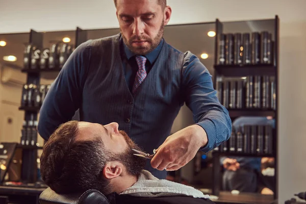 Brodaty Mężczyzna Siedzi Fotelu Fryzjer Podczas Fryzjer Modelowania Brodę Nożyczkami — Zdjęcie stockowe
