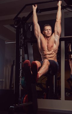 Şınav mı spor salonunda yatay çubuğu'nda bir kas gömleksiz adam.