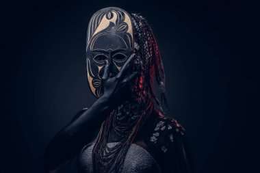 Yakın çekim bir cadıdan geleneksel kostüm giyen Yerli Afrikalı kabile portresi. Kalıcı makyaj kavramı. Karanlık bir arka plan üzerinde izole.