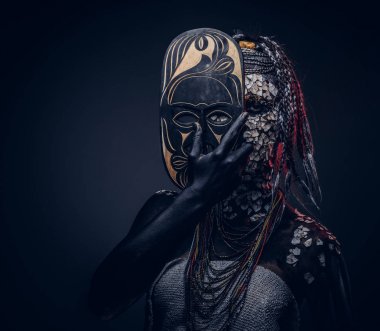 Yakın çekim bir cadıdan geleneksel kostüm giyen Yerli Afrikalı kabile portresi. Kalıcı makyaj kavramı. Karanlık bir arka plan üzerinde izole.