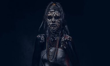 Yakın çekim bir cadıdan geleneksel kostüm giyen Yerli Afrikalı kabile portresi. Kalıcı makyaj kavramı. Karanlık bir arka plan üzerinde izole.