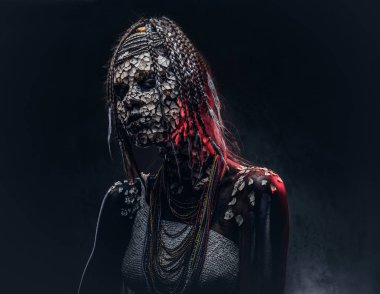 Yakın çekim bir cadıdan geleneksel kostüm giyen Yerli Afrikalı kabile portresi. Kalıcı makyaj kavramı. Karanlık bir arka plan üzerinde izole.