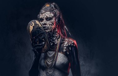 Taşlaşmış bir kırık Cilt ve dreadlocks, korkutucu Afrika şaman erkek portresi geleneksel maske karanlık bir arka plan üzerinde tutar. Kalıcı makyaj kavramı.