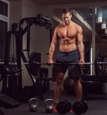 Kas gömleksiz vücut geliştirmeci erkek Deadlift ile bir spor salonunda bir halter yapıyor.