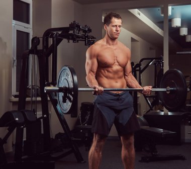 Kas gömleksiz vücut geliştirmeci erkek spor salonunda bir pazı üzerinde halter kaldırma.