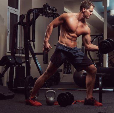 Spor salonunda dumbbells ile bir pazı egzersizleri yaparken kas vücut geliştirmeci adam.