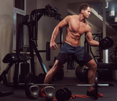 Spor salonunda dumbbells ile bir pazı egzersizleri yaparken kas vücut geliştirmeci adam.