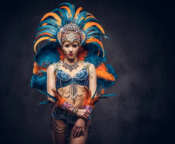 Studioporträt einer sexy Frau in einem farbenprächtigen Karnevalsfederanzug. isoliert auf dunklem Hintergrund. — Stockfoto