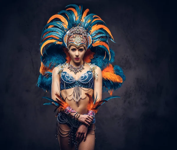 Studioporträt einer sexy Frau in einem farbenprächtigen Karnevalsfederanzug. isoliert auf dunklem Hintergrund. — Stockfoto