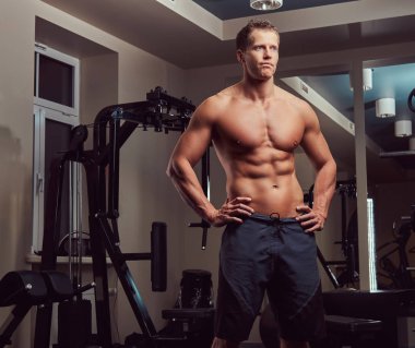 Spor salonunda poz yakışıklı kaslı gömleksiz vücut geliştirmeci.