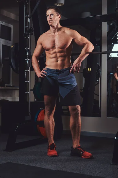 Gespierde shirtless man poseren met een barbell in de sportschool. — Stockfoto