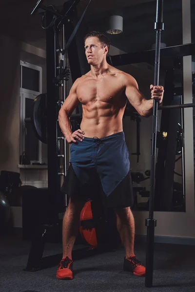 Gespierde shirtless man poseren met een barbell in de sportschool. — Stockfoto