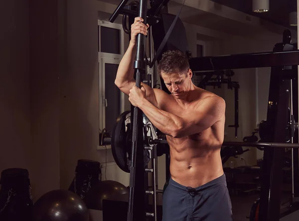 Homem sem camisa muscular posando com um sino na academia . — Fotografia de Stock