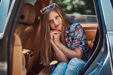 Polar tişört ve kot, araba açık bir kapı ile arka koltukta oturan gülümseyen güzel bir kız portresi.