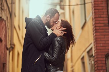 Çekici çift, sakallı bir adam ve bir arka plan üzerinde dış eski Avrupa sokak öpüşme esmer kız.