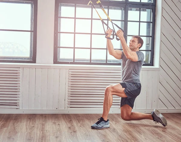 Muscular fitness male doing exercise with TRX. Functional workout at home with TRX loops. — Stock Photo, Image