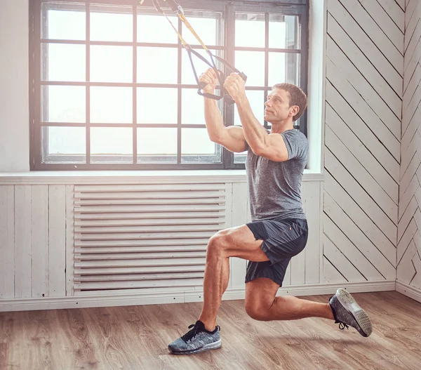 Muskulös fitness hane gör träning med Trx. funktionell träning hemma med Trx loopar. — Stockfoto