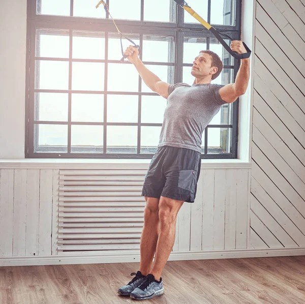 Muscular fitness male doing exercise with TRX. Functional workout at home with TRX loops. — Stock Photo, Image