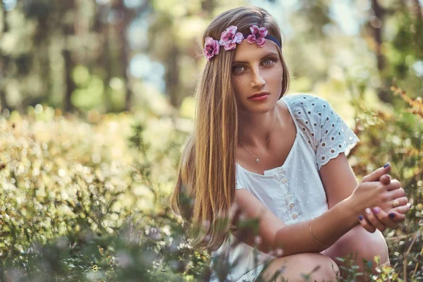 Hermosa mujer en un vestido blanco y corona púrpura en la cabeza posando en un bosque de otoño verde . — Foto de Stock